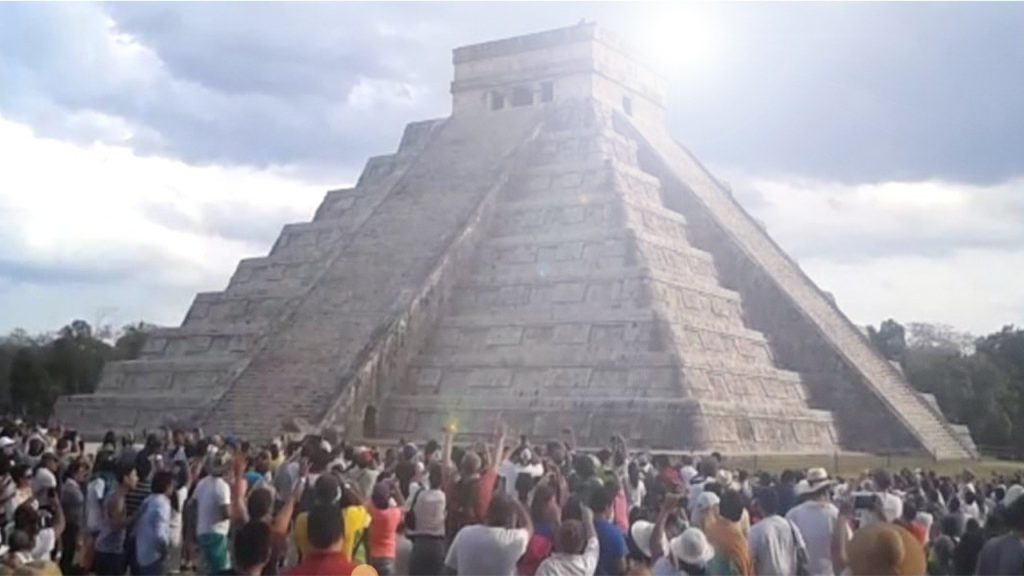 Una piramide maya con una folla ai suoi piedi